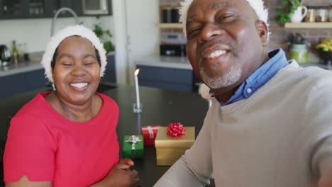 happy african american senior couple in santa hats on video call at christmas time