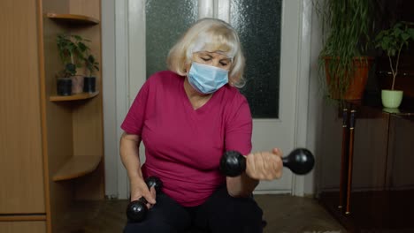 senior mature grandmother woman in sportswear doing weightlifting dumbbell exercising at home