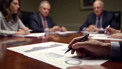 a group of professionals engaged in a strategic discussion with focus on visual data analysis in a conference setting, highlighting charts and graphs