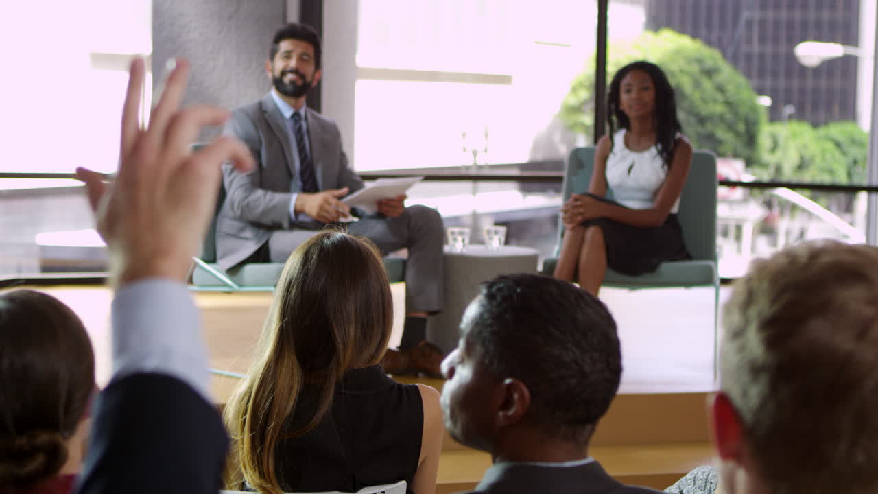 Male and female seminar speakers take question from audience, rack focus shot on R3D