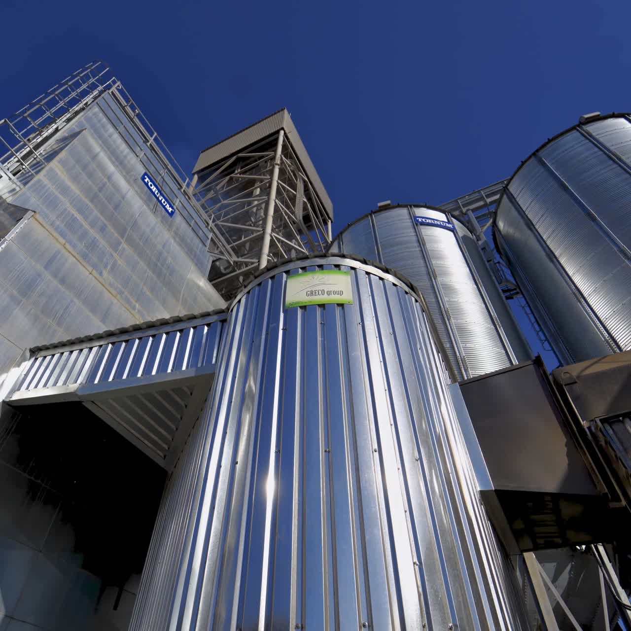 Metallic warehouse outdoors. Large aluminium containers against blue sky. Modern equipment for agribusiness. Exterior of new plant.