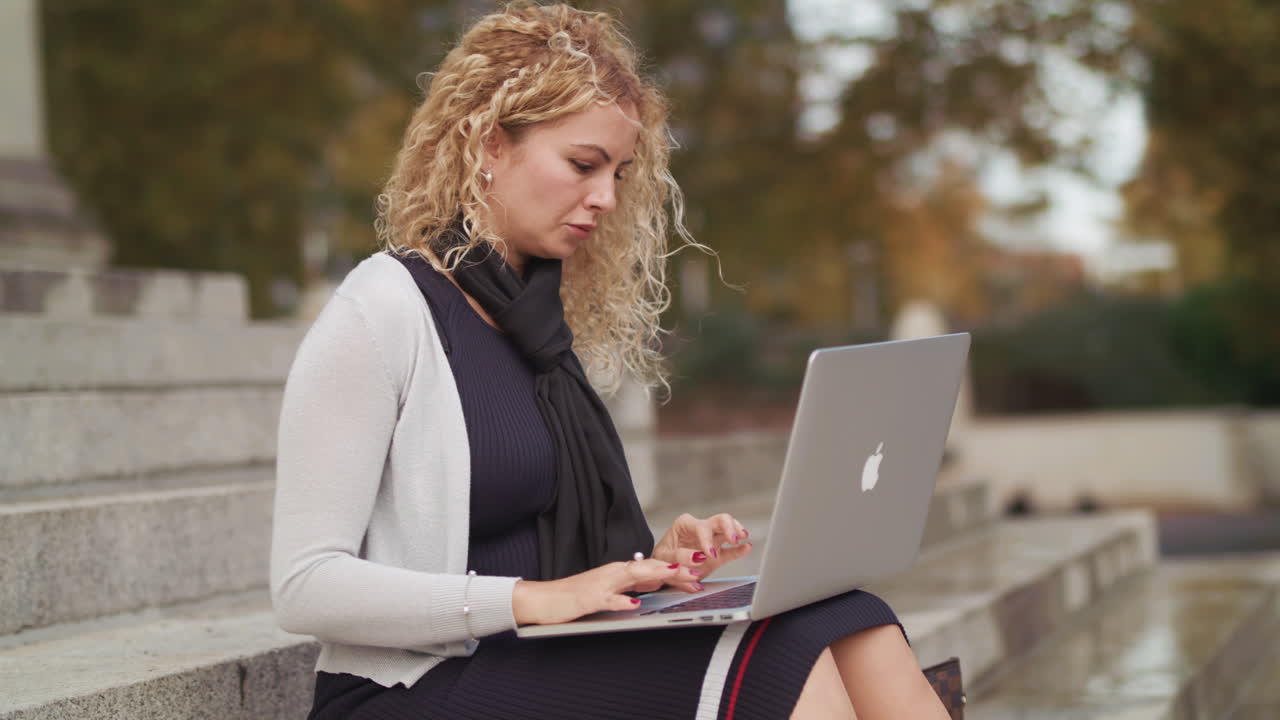 외부에서 노트북을 사용하는 매력적인 여성이 일을 끝내고 기뻐합니다.