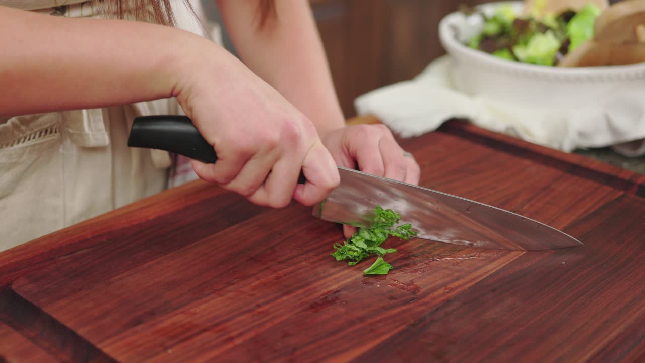cortar hierbas frescas en una tabla de cortar de madera, mostrando un proceso de cocción
