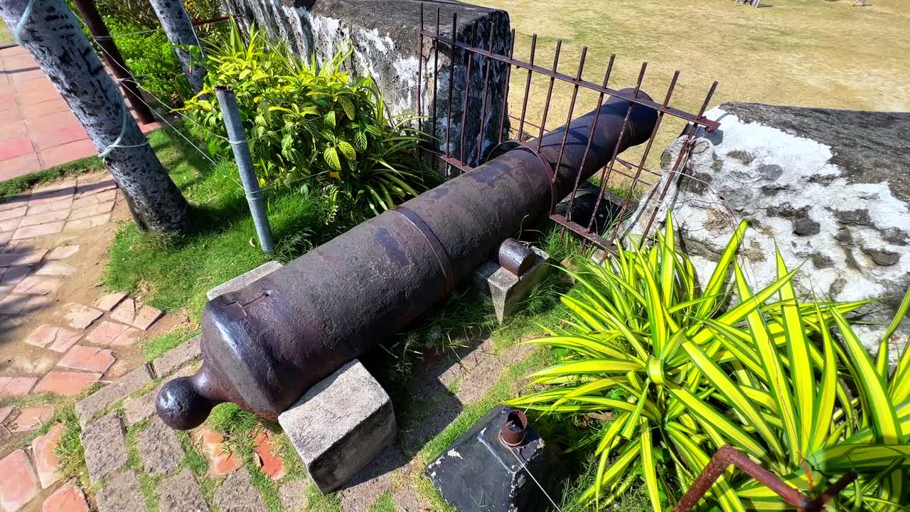Ancient iron cannon on stone supports, surrounded by greenery — ideal for colonial, military, or historical tourism themes