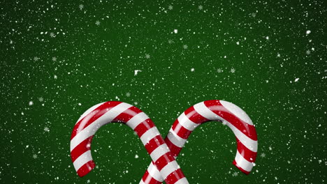 animation of snow falling over christmas candies on green background