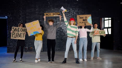 young environmental activists with placards and megaphone protesting against climate change inaction and looking at the camera