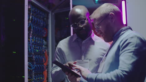 it professionals working in a server room with a tablet