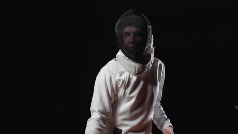 a young man wearing a fencing mask and white uniform prepares for a fencing match.