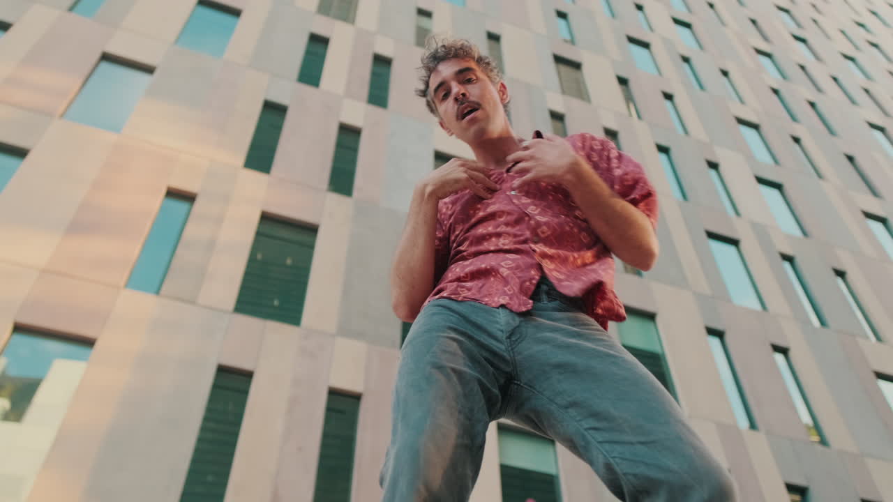 Ung mand danser udtryksfuldt foran en moderne bygning