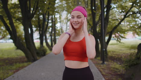 Portrait-of-athletic-sport-runner-girl-training,-listening-favorite-music-song-in-earphones-in-park