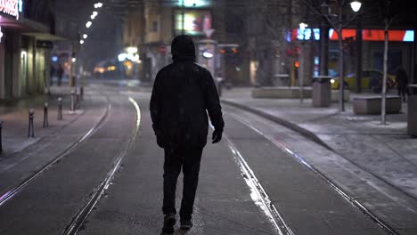 solo person stands still as snow falls around them on empty side street