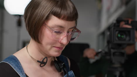 asistente femenina en el set de filmación en el estudio escribiendo detalles de producción de película o video en clapperboard o pizarra 1