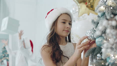 focused girl decorating christmas tree in living room