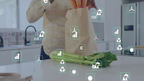 animación de iconos ecológicos sobre mujer biracial con compras de verduras en la cocina