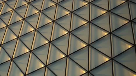 intricate geometric patterns captured on a modern architecturally designed facade, showcasing light reflections across triangular glass elements
