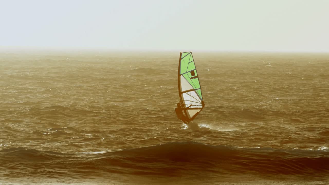 surfista masculino haciendo windsurf en la playa 4k