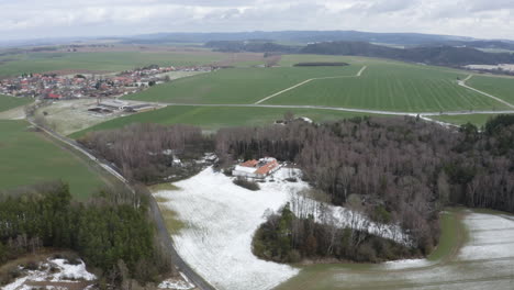 Granja-Con-Campo-Cubierto-De-Nieve-Cerca-Del-Pueblo-En-El-Campo-Checo,-Drone