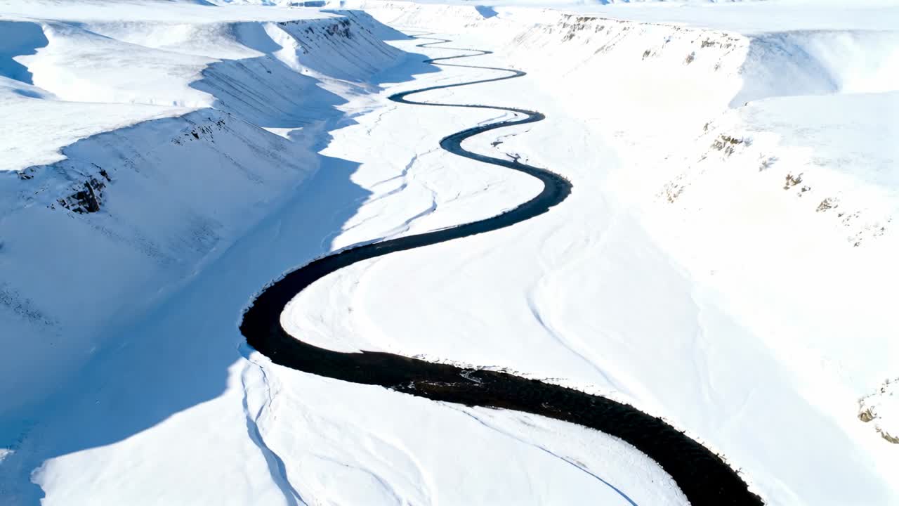 Tracking aircraft following dark meandering river through snowfields, revealing upstream curves