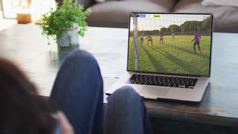 Man-using-laptop-with-diverse-male-soccer-players-playing-match-on-screen