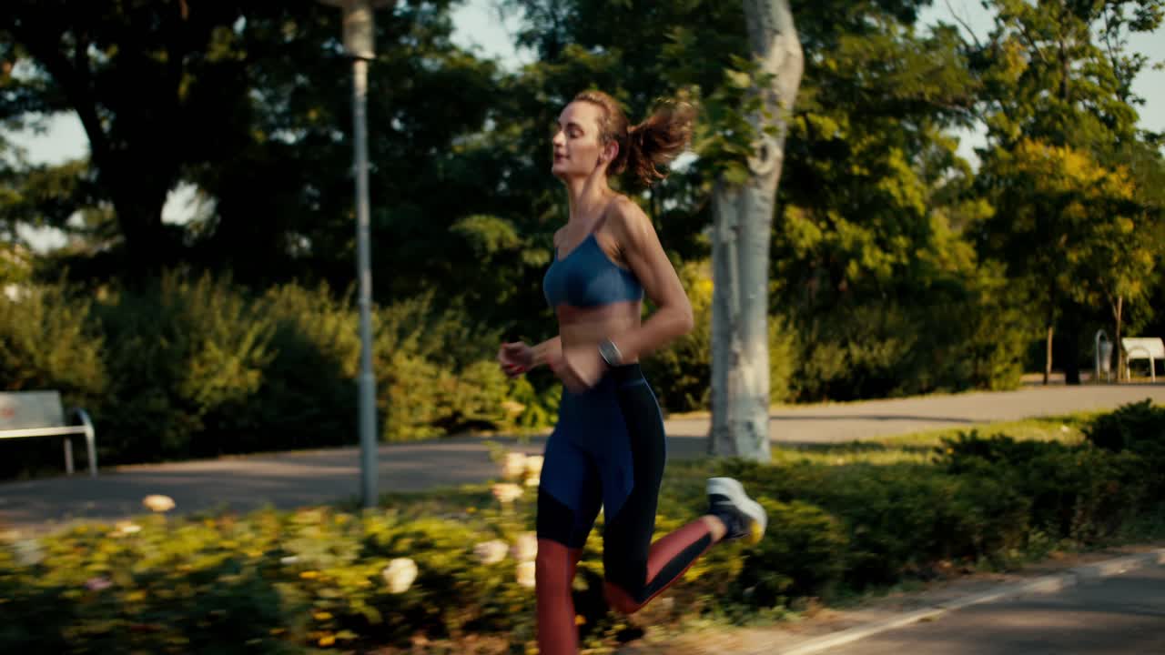 una chica deportiva en un uniforme deportivo de verano corre a velocidad en el parque de la mañana. fitness y correr para mejorar su salud y cuerpo
