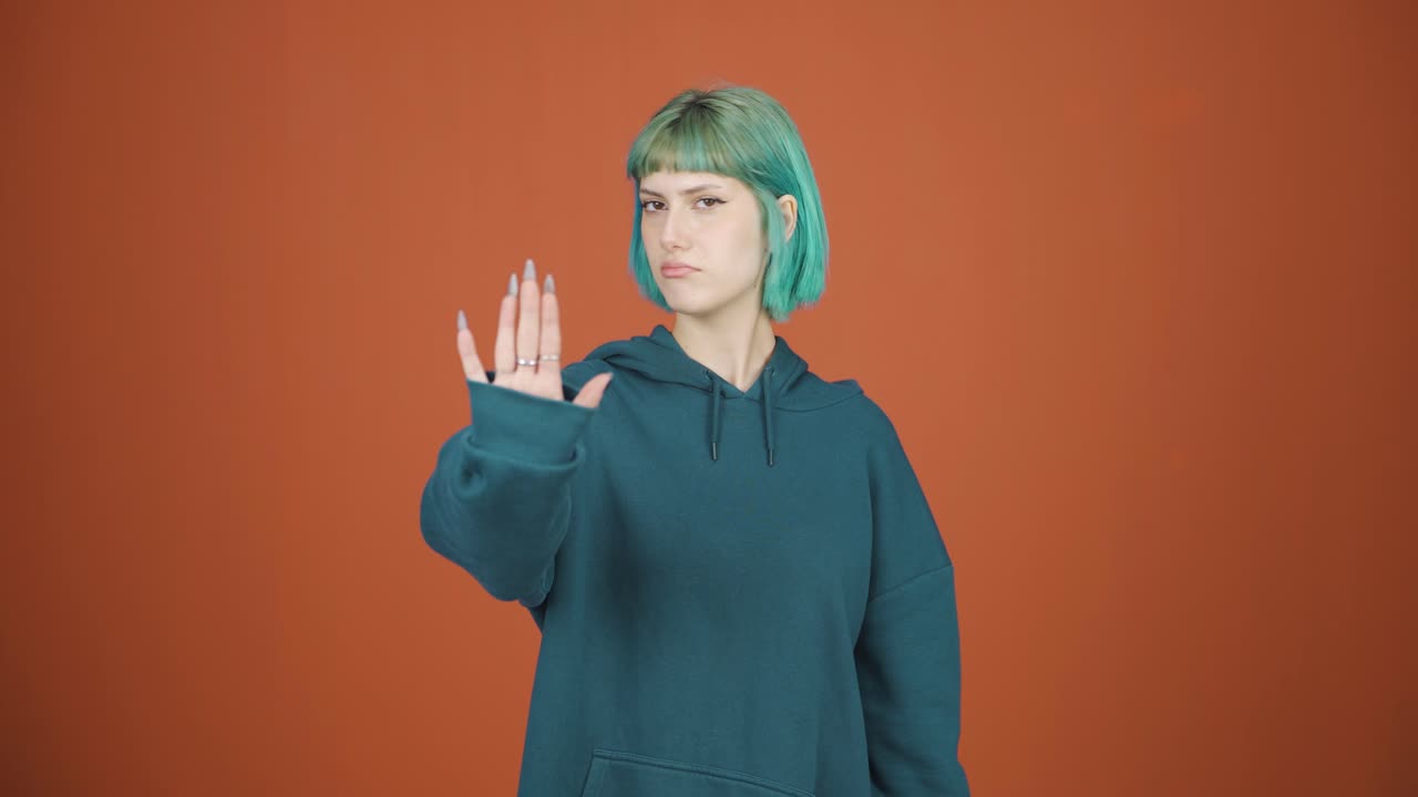 mujer joven haciendo una señal de alto para la cámara.