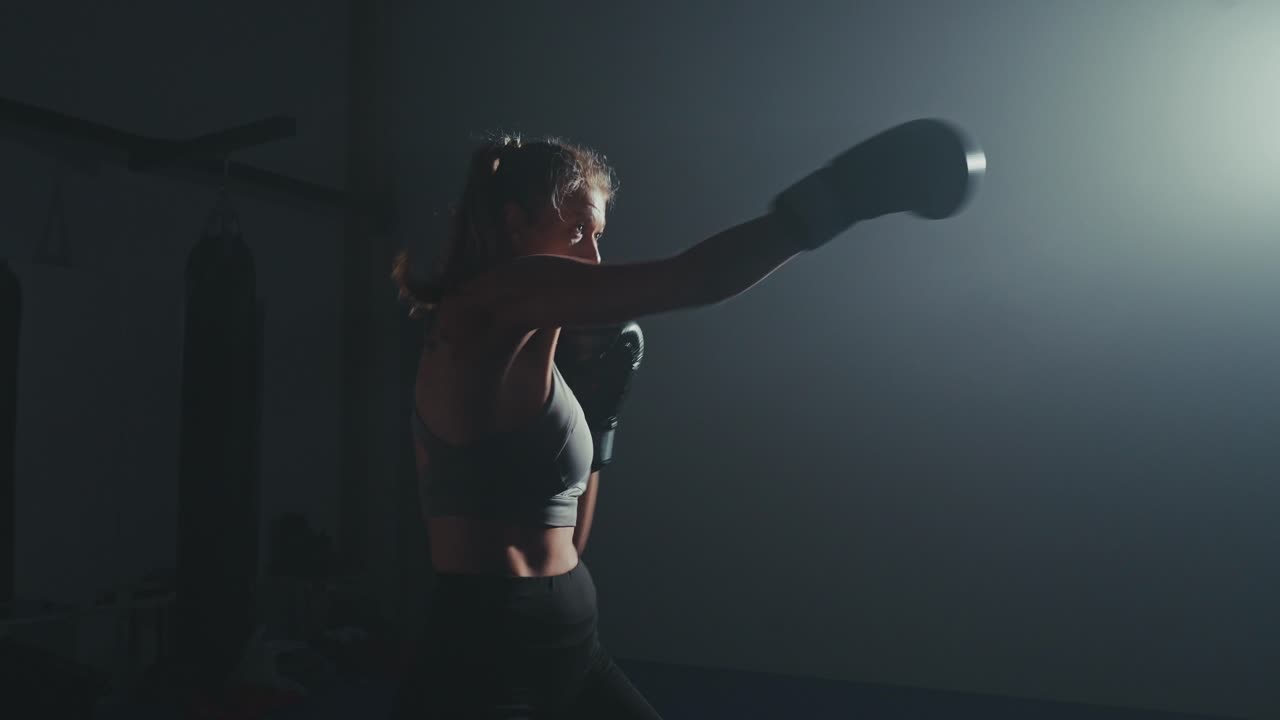 Strong Woman Shadow Boxing and Kicking in a Dark Training Room