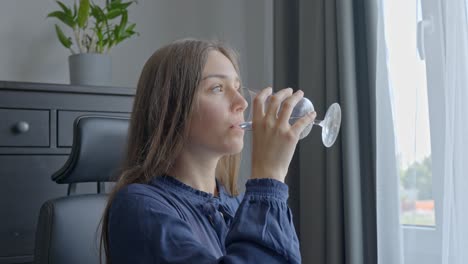 joven morena bebiendo agua mientras está sentada en la oficina, vista de retrato