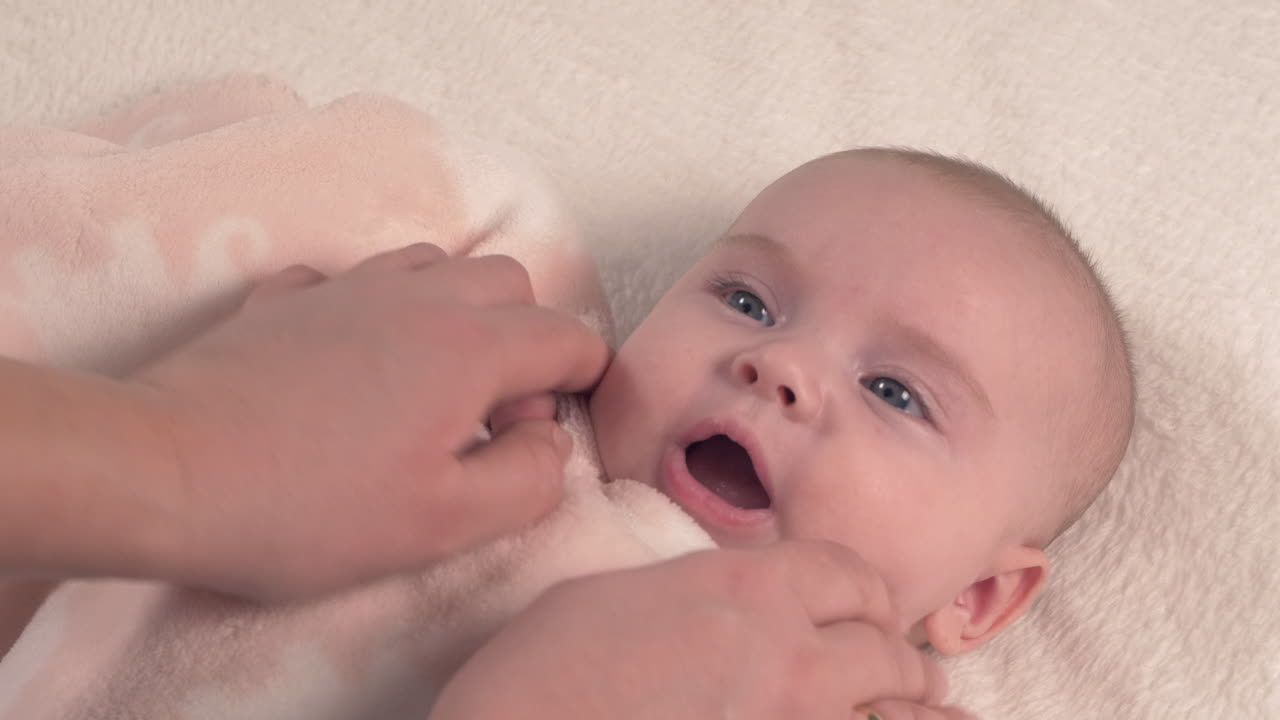 el hermoso bebé recién nacido está acostado en la cama y muestra las manos y los pies, la madre juega con el bebé y la cubre con una colcha acogedora, 4k 60p apple prores422, con grabadora de átomos externos-5
