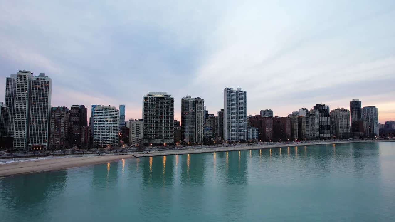 aumento de la antena de la puesta de sol sobre el lago michigan chicago que revela los suburbios de la ciudad con una vista panorámica de la puesta de sol