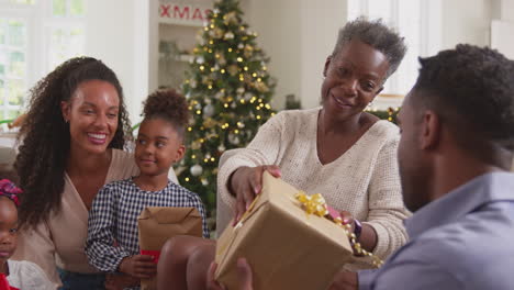 Familia-Multigeneracional-Celebrando-La-Navidad-En-Casa-Abriendo-Regalos-Juntos