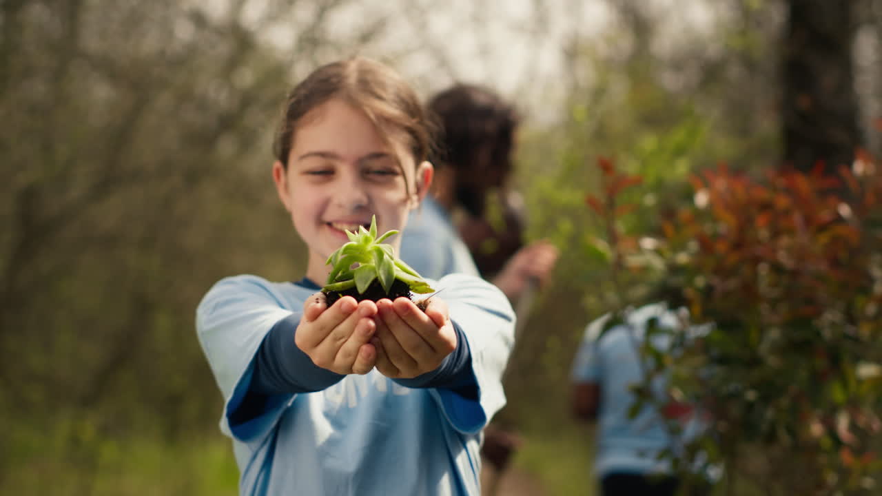 niño voluntario sosteniendo una pequeña plántula con suelo natural en las manos