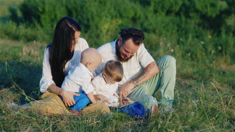 Young-Stylishly-Dressed-Parents-Play-With-Their-Sons-On-A-Tablet-Outdoor-Recreation