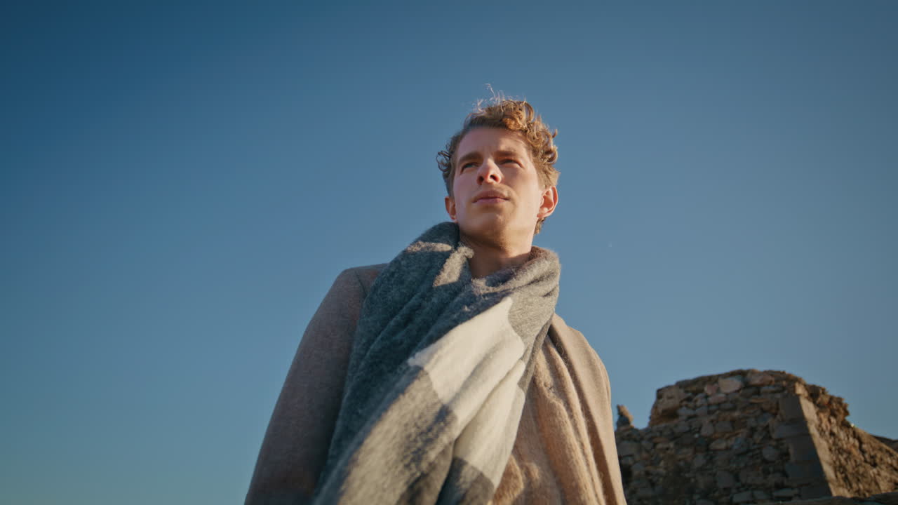 Contemplative guy looking nature at windy weather bottom view. Man in sunlight