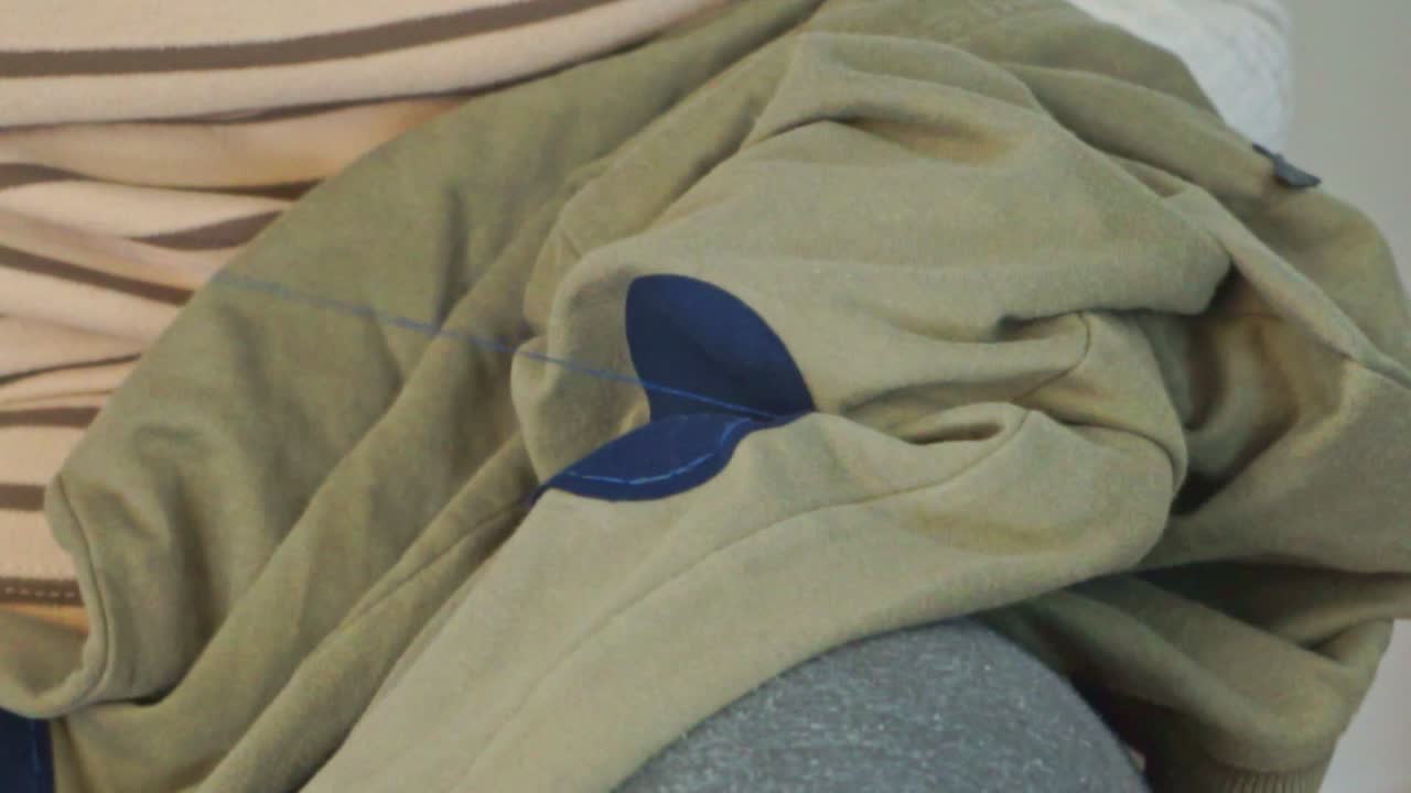 그녀의 손자의 바지에 패치를 바느질 백인 성숙한 할머니