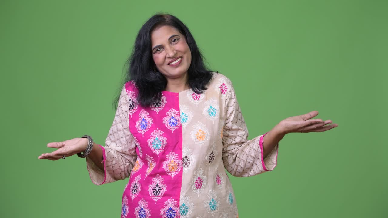 зрелая красивая индийская женщина, поднимающая плечами и выглядящая озадаченной.