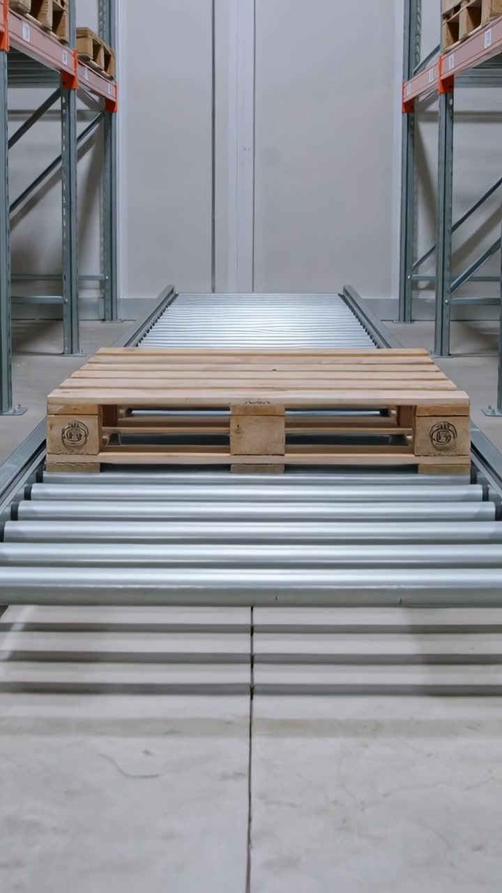 Video verticale: Nastro trasportatore che si attiva, pallet di legno che si muove lungo i rulli in magazzino, per il trasporto.