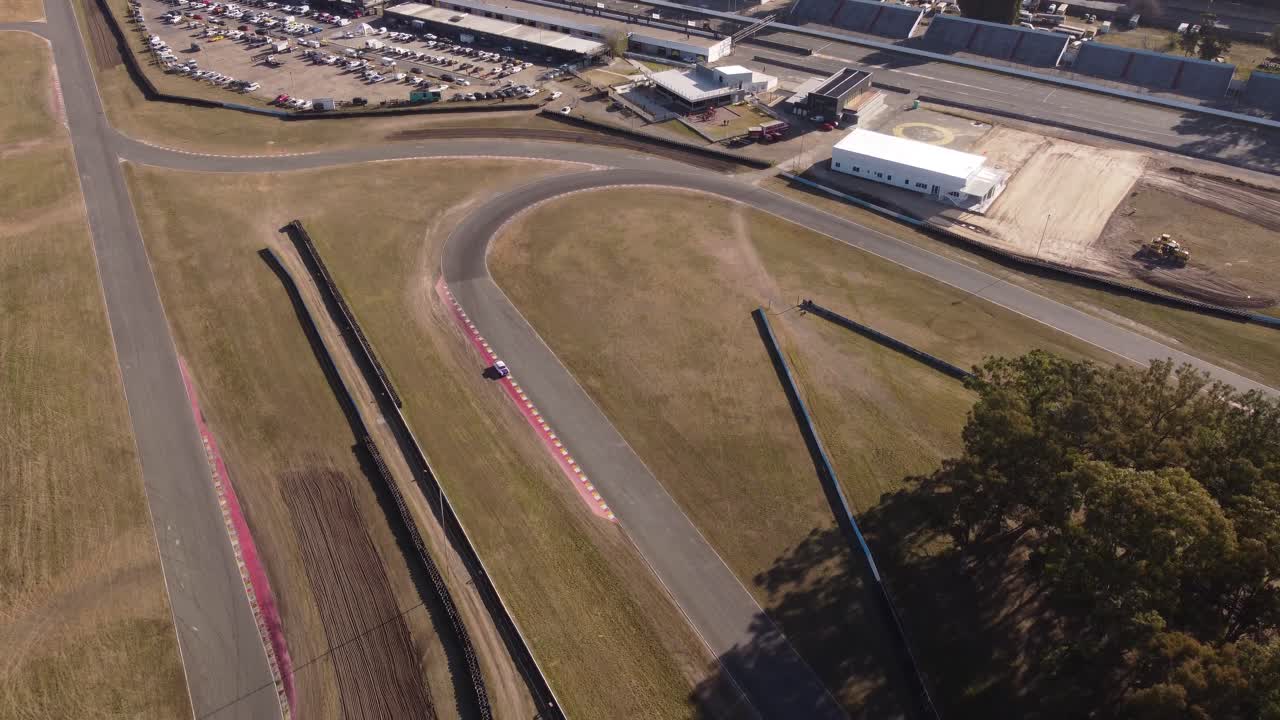 aerial drone tilt down view of white classic vintage race car driving on buenos aires racetrack circuit (부에노스 아이레스 레이스 트랙 서에서 운전하는 색 클래식 빈티지 레이스카의 시상)