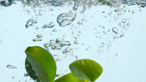 las cuñas de cal caen agua en cámara súper lenta de cerca. líquido de salpicaduras de cítricos.