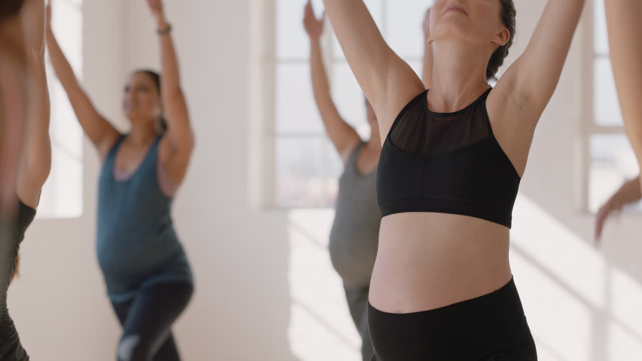 ritratto di lezione di yoga giovane donna caucasica incinta che pratica pone tenendo la pancia godendo di esercizio di gruppo in sala fitness