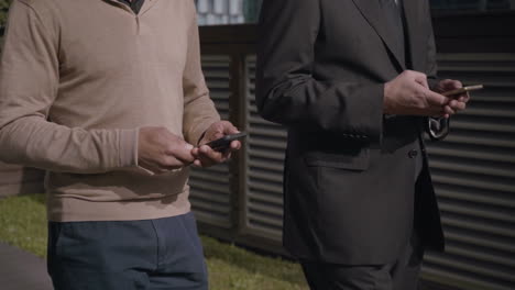 adult businessmen walking and using smartphones