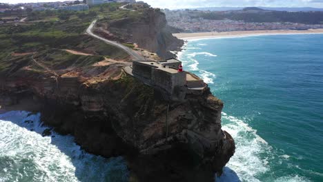 aerial view of lighthouse in nazaré with steep high rocky cliff