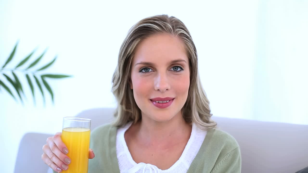 hermosa mujer bebiendo un vaso de jugo de naranja