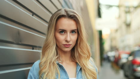 close-up view of charming young blonde woman with blue eyes looking and smiling at the camera