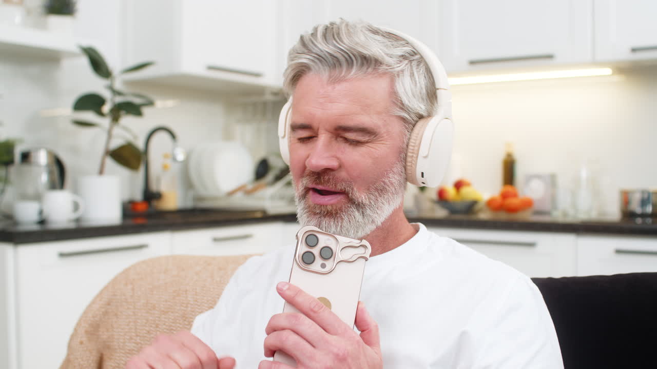 Middleaged man listens to favorite music with headphones nods to rhythm smiles rests during break