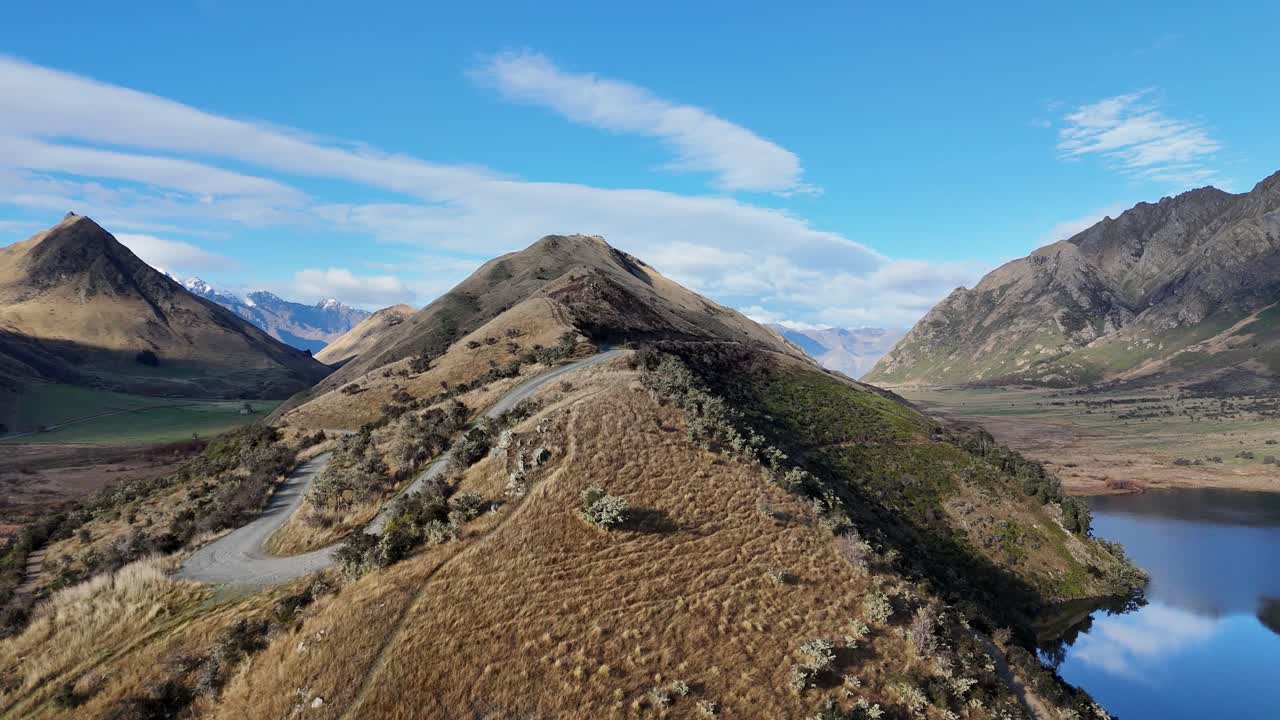 Drone footage captures a scenic flight over Lake Moke, showcasing mountainous landscapes and serene waters under clear skies