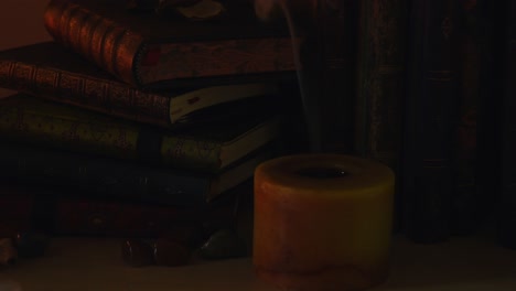 close up background of an ancient library, next to a frieplace, with old books and a candle being blown off