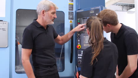 Two-Apprentices-Working-With-Engineer-On-CNC-Machinery