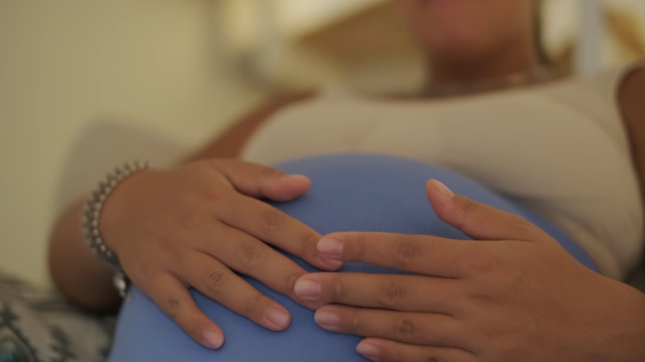 A pregnant woman enjoying her daily routine at home, relaxing in the living room and eating in the kitchen. The scene highlights comfort, maternity, and moments of self-care in a cozy setting