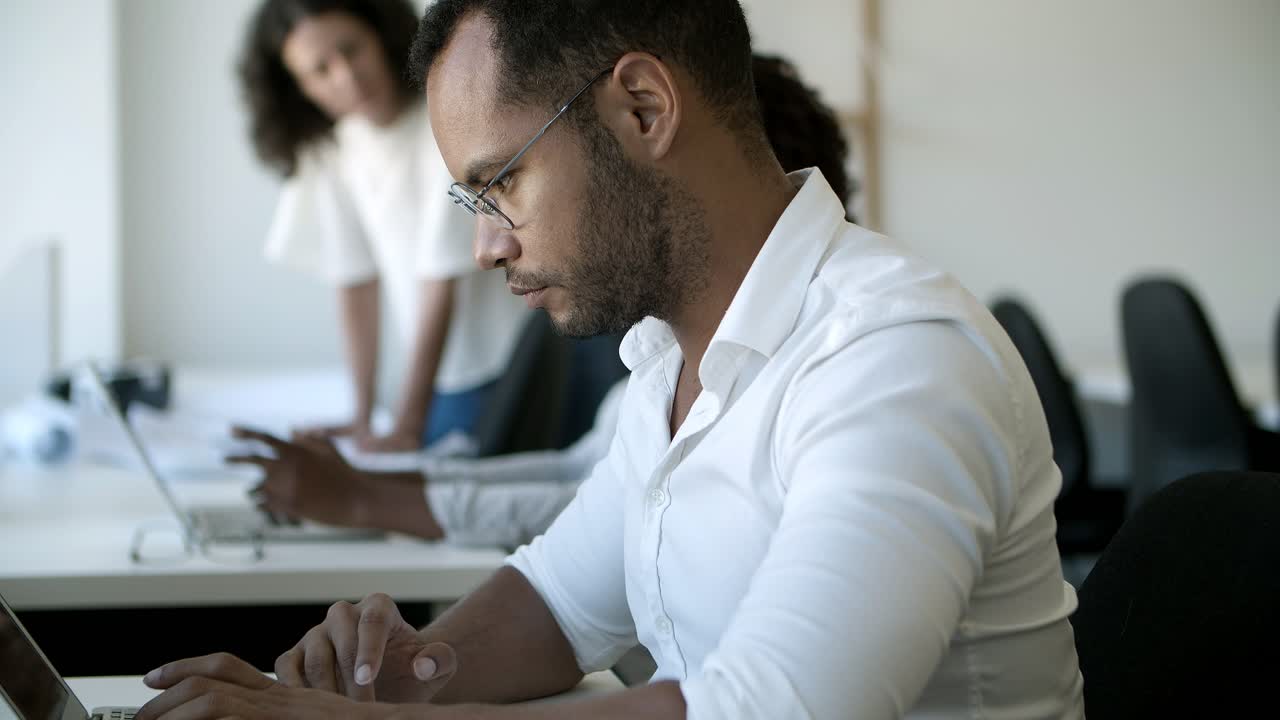 vista de cerca de un trabajador masculino enfocado escribiendo en una computadora portátil.