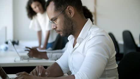 closeup view of focused male worker typing on laptop.